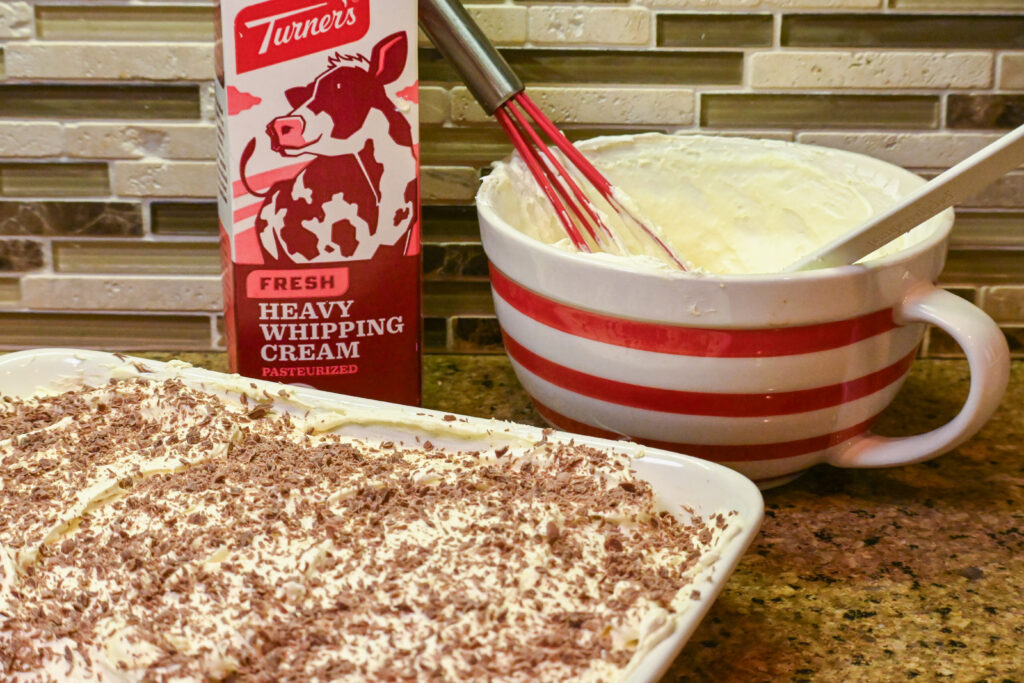 Chocolate Pudding dessert on a kitchen counter with a carton of Heavy Whipping Cream and a mixing bowl in the background.